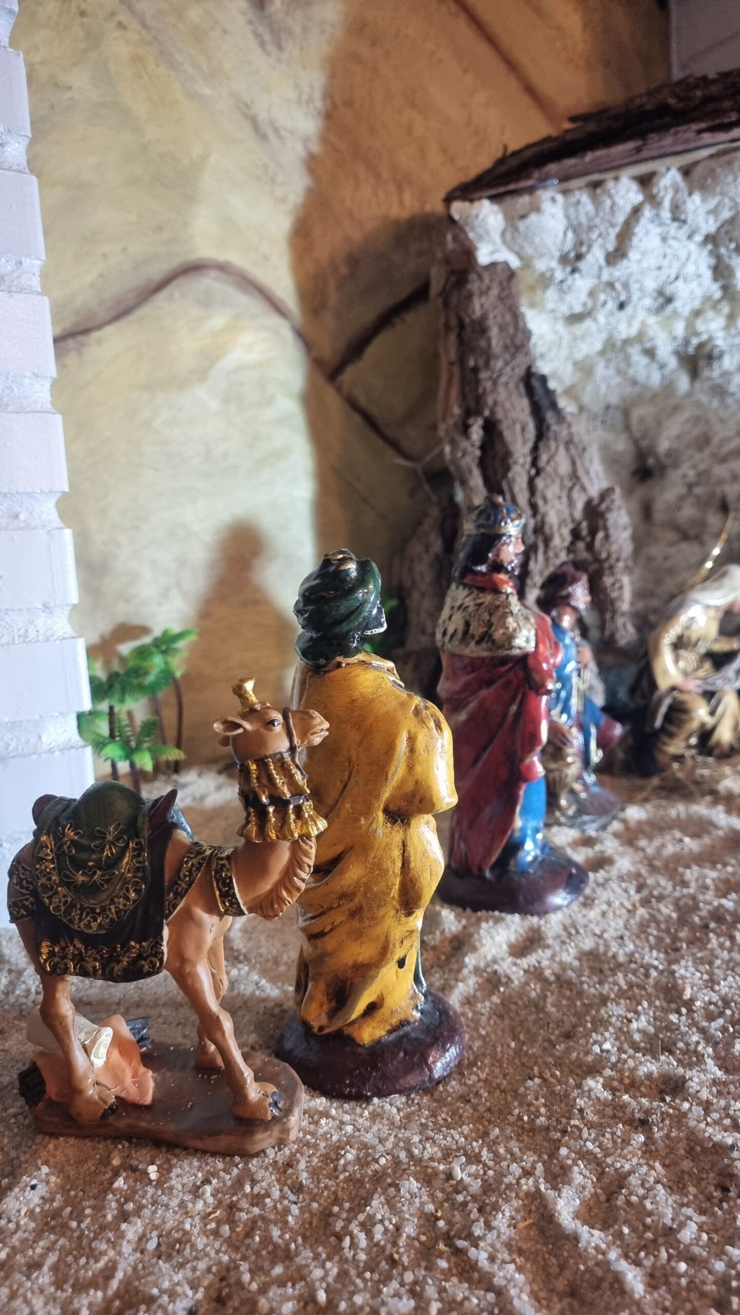 Vista posterior de los Reyes Magos y uno de los camellos, integrados en la escena del desierto del belén.