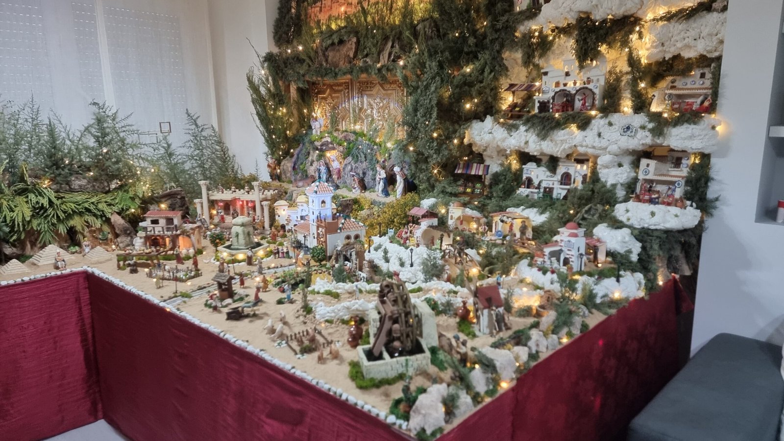 Vista parcial del belén en la que se aprecian distintos elementos del conjunto, como la iglesia, las fuentes y varias escenas distribuidas a lo largo del recorrido.