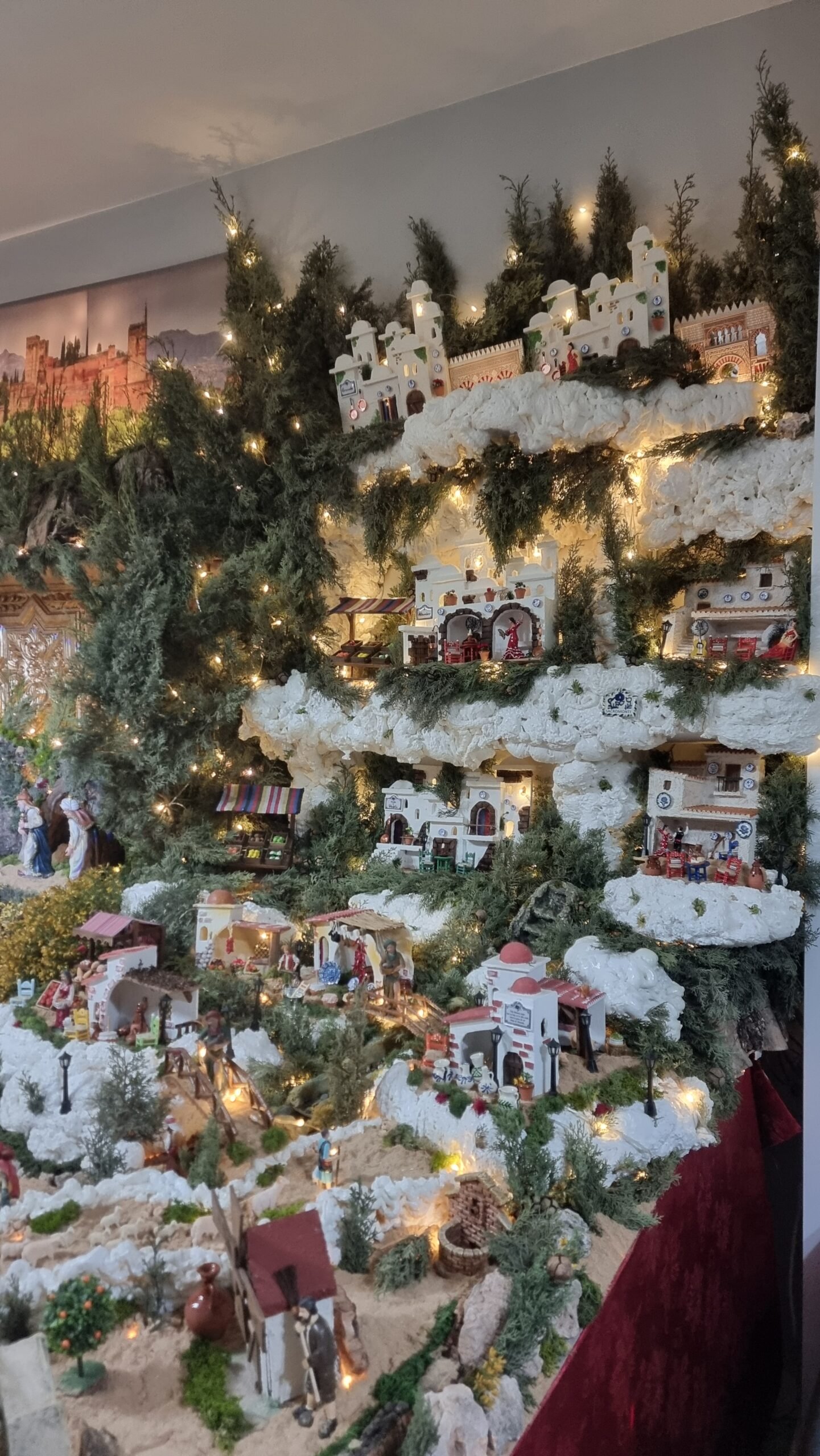 Detalle de la parte derecha del belén, donde se recrean las cuevas del Sacromonte, integradas en la pared del salón como parte de la escenografía.