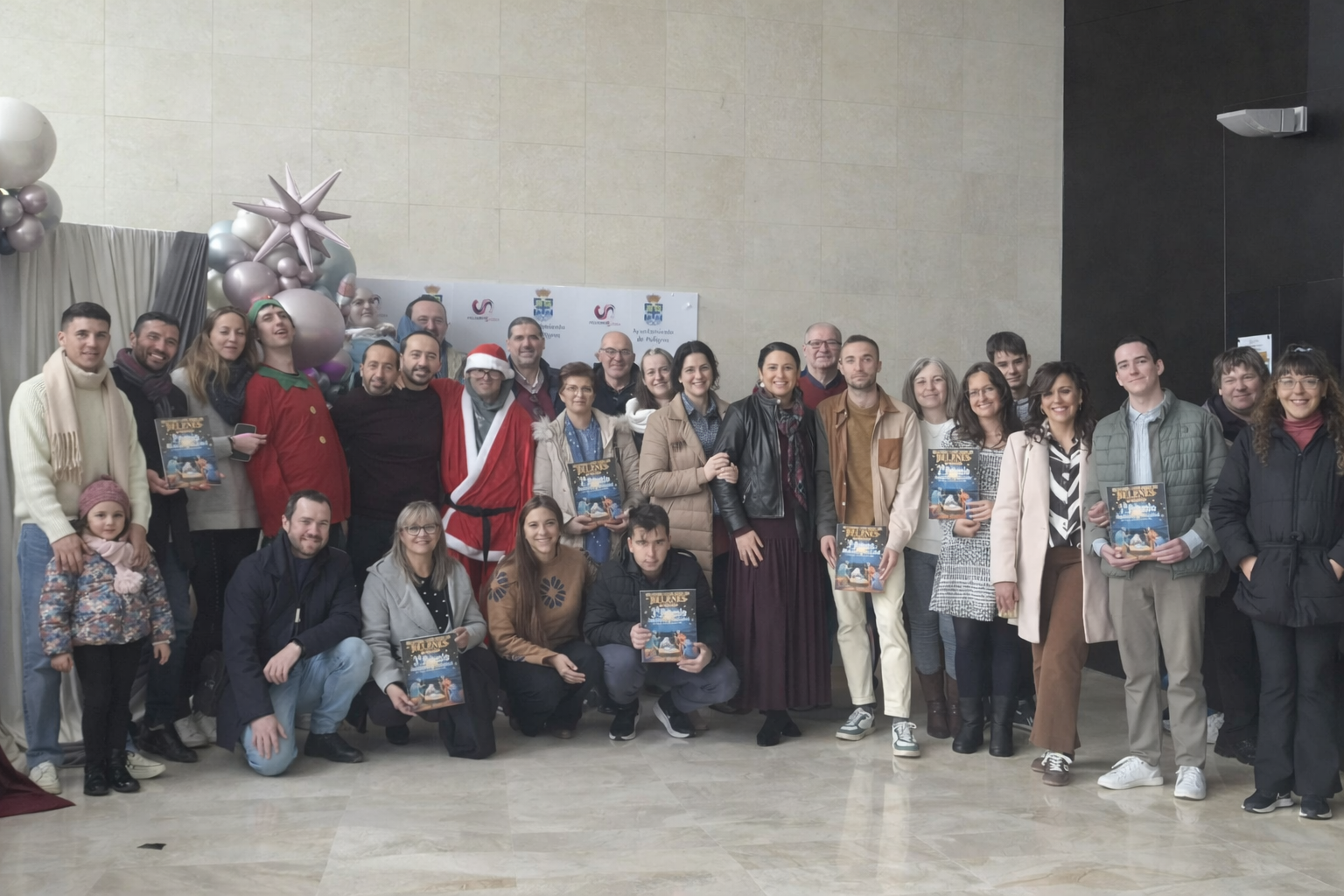 Foto de familia de participantes, premiados y autoridades municipales en el vestíbulo del Teatro Pablo Neruda, tras la entrega de premios del II Concurso Municipal de Belenes de Peligros.