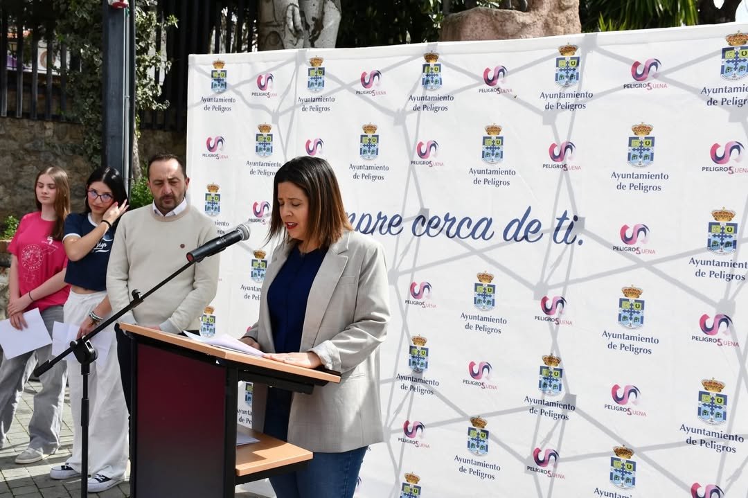 Luisa Zúñiga, concejala de Igualdad del Ayuntamiento de Peligros, durante su intervención en la inauguración de la exposición, con el alcalde Roberto García al fondo.